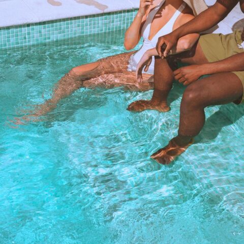Two friends relaxing together in sunny pool.