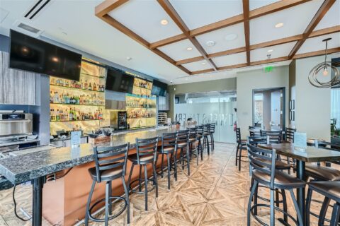 Towers Tavern with stone bar top, tall stools, well stocked bar, and large TVs.