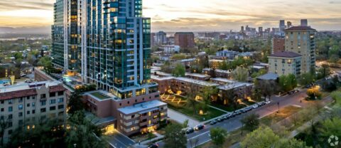 Aerial view of Country Club Towers & Gardens at dusk with glowing lights and distant sunset.