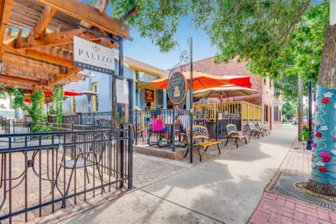 Cherry Creek sidewalk with tall trees and restaurants with patio dining.