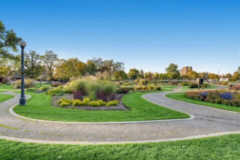 Park with green lawns, walking paths, and lush flower beds.