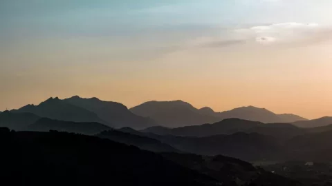 Distant mountains under cloudy sunset skies.